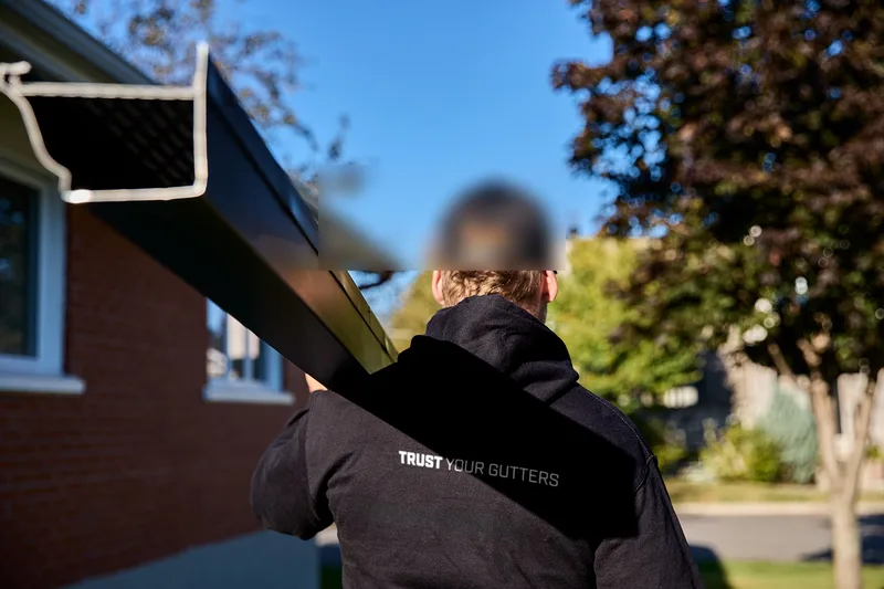 Installer carrying black gutter stock for a guard-ready system